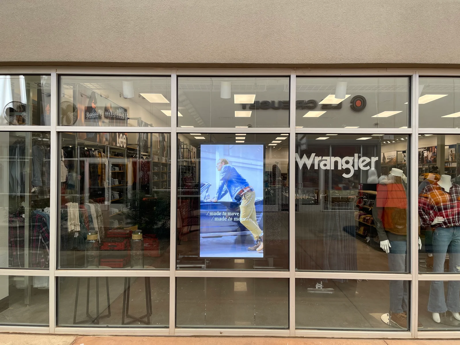 Lee and Wrangler outlet storefront with a portrait window display installed behind the glass by CrownTV.